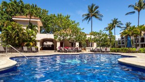 Una piscina con sillas de descanso y palmeras.