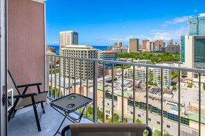 A balcony with a view of a cityscape, including high-rise buildings and a body of water. - Marine Surf Waikiki w/ Beach Gear & Parking! (Honolulu)