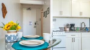 Une cuisine moderne avec des meubles blancs, une cuisinière et un plan de travail équipé de divers appareils.