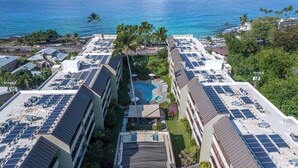 Een hotel met meerdere verdiepingen, zonnepanelen op het dak, een zwembad en uitzicht op de oceaan.