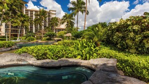 A resort with a swimming pool, palm trees, and a large building in the background.