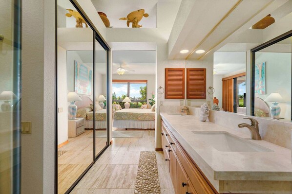 A modern bathroom with a double sink, large mirror, and a view of the garden through the glass door.