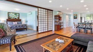 A spacious living area with a traditional sliding door, a dining table with chairs, a sofa, and a coffee table.
