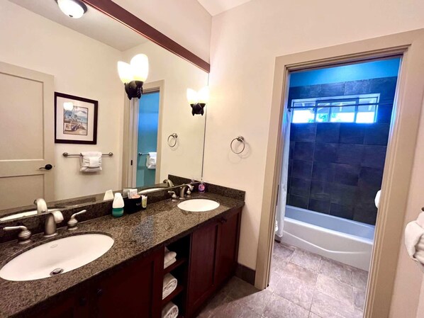 A bathroom with two sinks, a large mirror, and a shower.