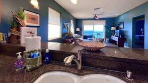 A modern kitchen with a granite countertop, stainless steel sink, and overhead pendant lighting.
