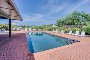 Relax by the serene pool surrounded by lush greenery and comfortable lounge chairs.