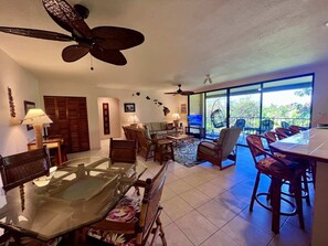 Amplia sala de estar con mesa de comedor de vidrio, asientos cómodos y un balcón con mobiliario exterior.