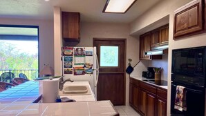 Una cocina con armarios de madera, un refrigerador, un microondas y un lavamanos.