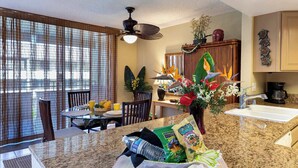 A kitchen with a granite countertop, a dining area with a table and chairs, and a window with blinds.