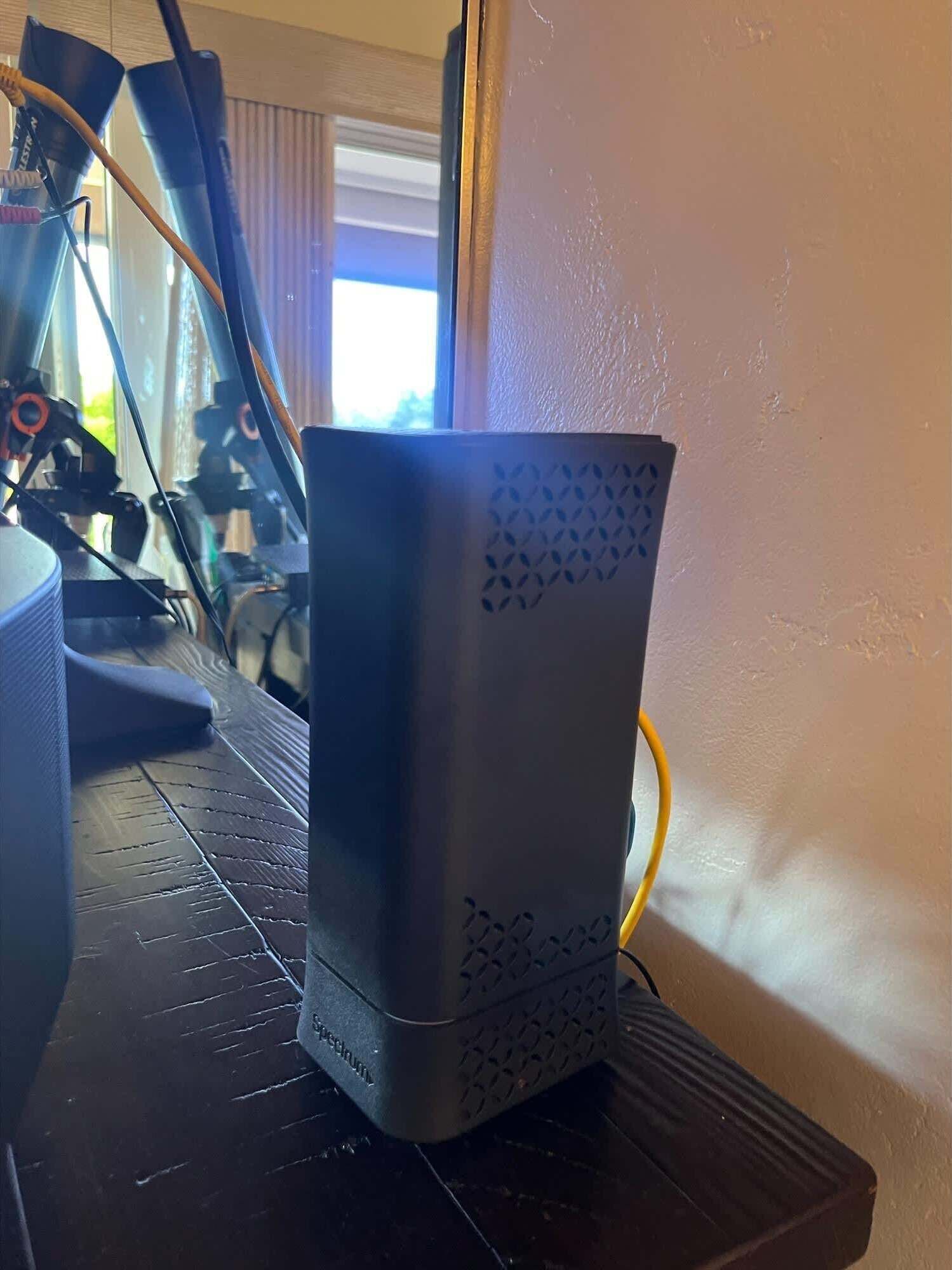 Un altavoz negro con textura sobre una superficie negra, con una ventana al fondo.