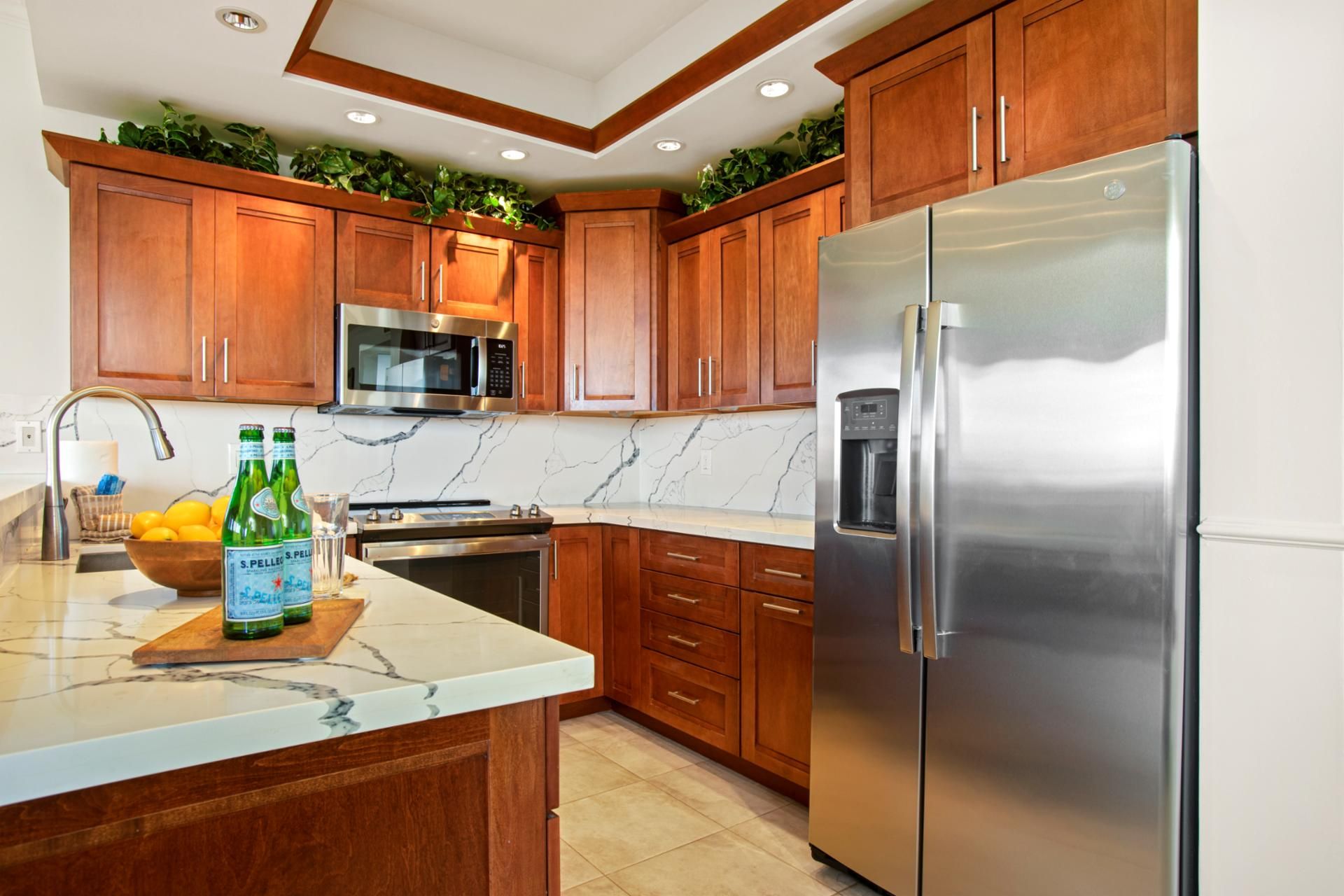 A kitchen with wooden cabinets, a stainless steel refrigerator, a microwave, and a stove.