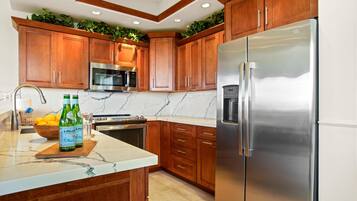 A kitchen with wooden cabinets, a stainless steel refrigerator, a microwave, and a stove.