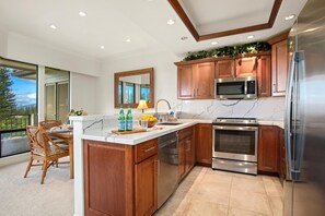 A modern kitchen with wooden cabinets, stainless steel appliances, and a marble countertop.