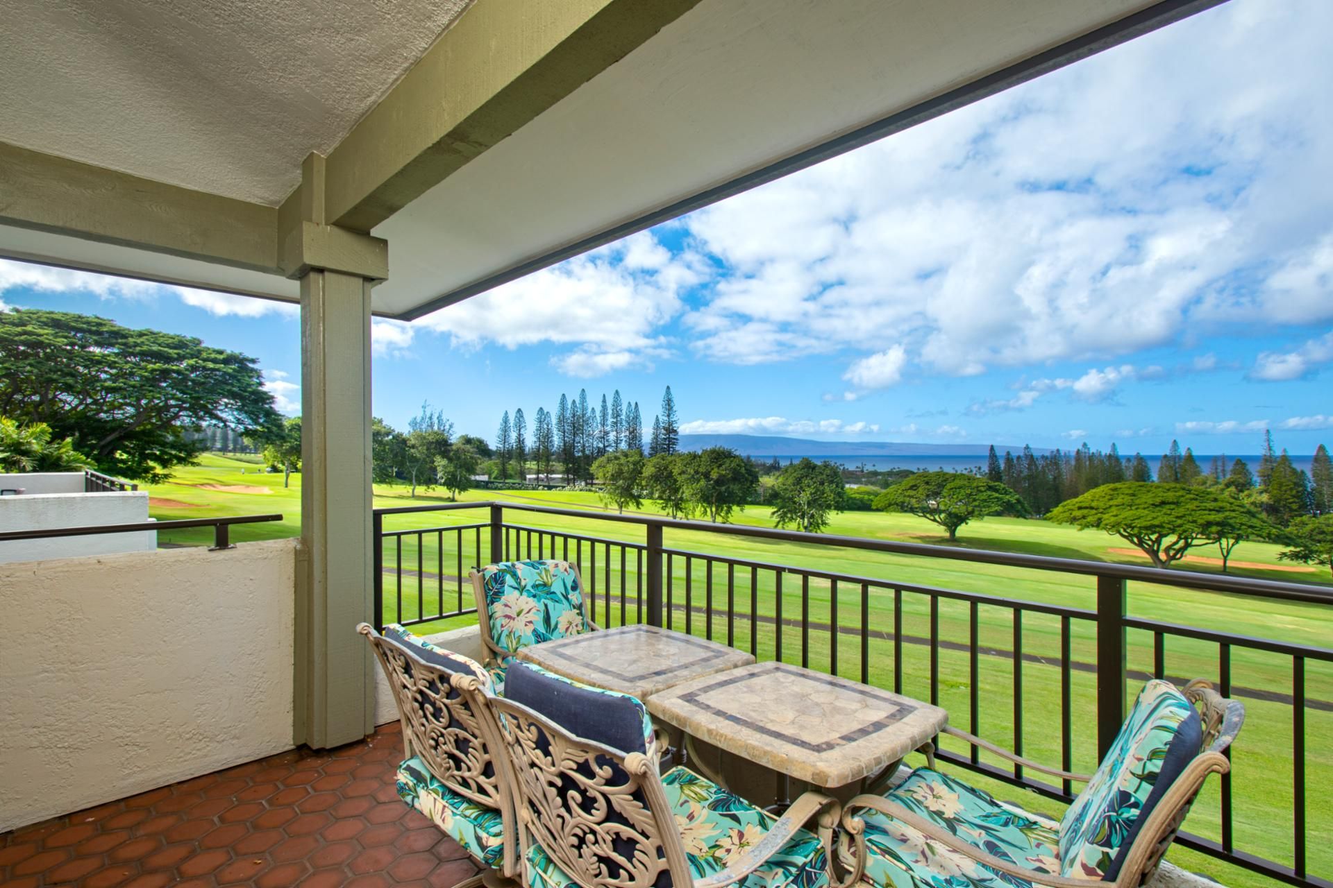 A balcony with wicker furniture and a view of a golf course.
