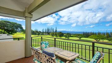A balcony with wicker furniture and a view of a golf course.