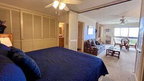 Ein Schlafzimmer mit einem großen Bett, einem Deckenventilator und Blick auf einen Balkon mit Korbmöbeln.