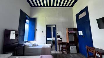 Habitación de hotel con dos camas, un escritorio, una silla, un armario y un televisor.