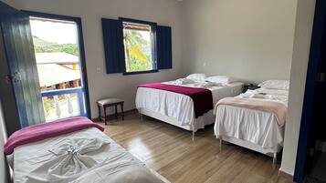 Habitación de hotel con dos camas, ventana con vistas a la vegetación y suelo de madera.