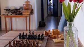 A chessboard on a wooden table with a vase of red tulips and a framed picture on the wall. - Pousada Usina Paraíso (Astolfo Dutra)