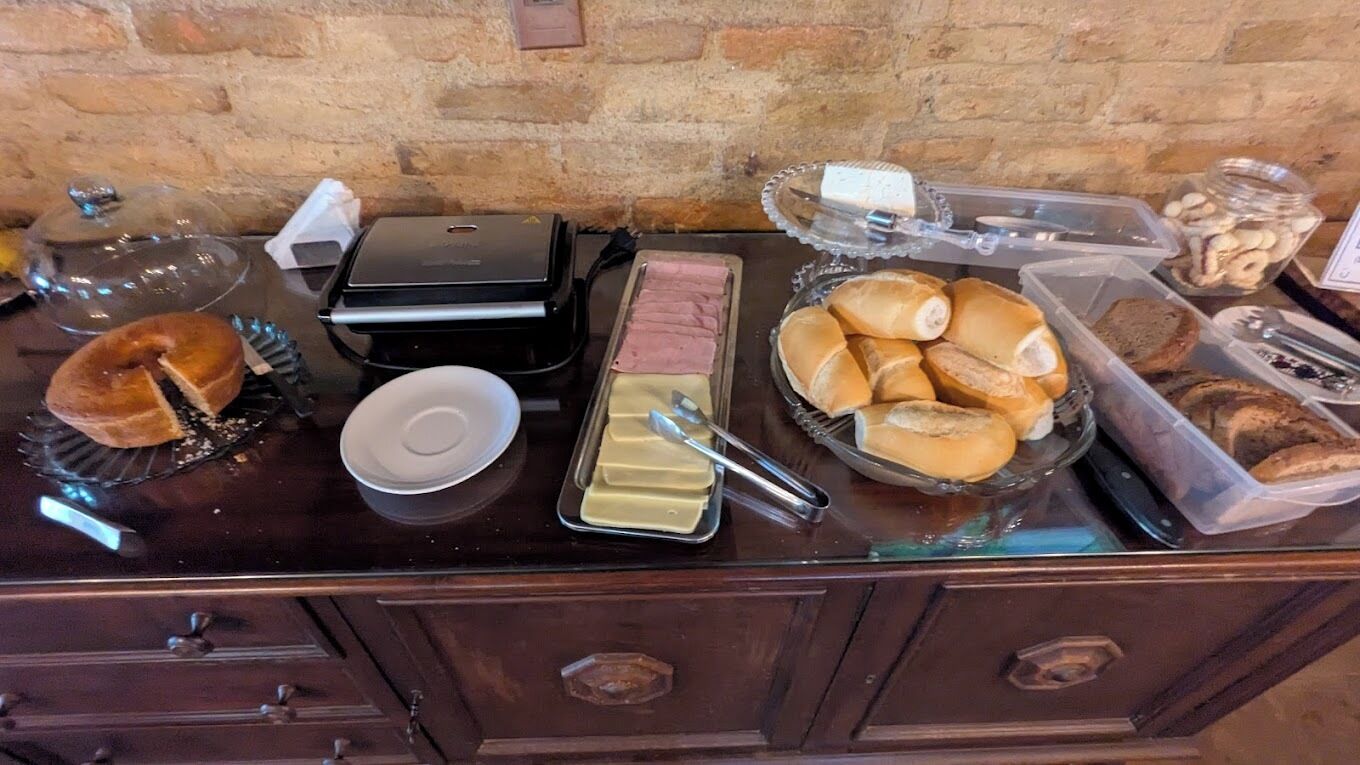 Une table de buffet proposant divers plats, notamment des pâtisseries, un assortiment de fromages et un récipient rempli de biscuits.
