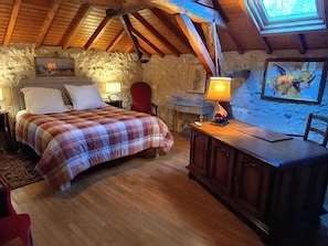 A bedroom with a bed, a desk, a chair, a lamp, and a painting on the wall. - Charming house in Brantôme, pets allowed, parking included (Brantôme en Périgord-Brantôme en Périgord)