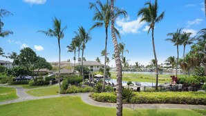 Un complexe hôtelier doté d’une piscine, de palmiers et, au loin, d’un terrain de golf.