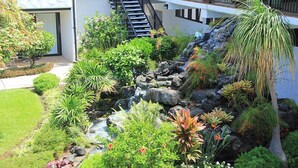 A landscaped garden with a small waterfall, a staircase, and a variety of plants.