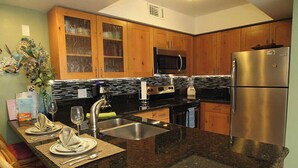 A kitchen with granite countertops, wooden cabinets, stainless steel appliances, and a built-in microwave.