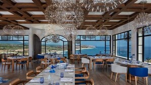 A restaurant with a long table set for dining, large windows with a view of the sea, and hanging crystal chandeliers. - 4BD Oceanfront Unit Vista Encantada Cabo (Cabo San Lucas)