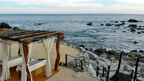 A beachside cabana with a bench and a table, overlooking the ocean. - 4BD Oceanfront Unit Vista Encantada Cabo (Cabo San Lucas)