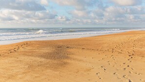 A sandy beach with footprints leading to the water, a clear sky, and waves approaching the shore. - Le Landais - Wifi - Loggia - Plage (Tarnos)