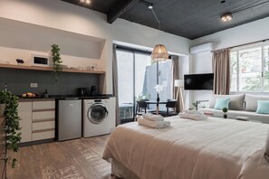 A modern bedroom with a large bed, a washing machine, a dining area, and a TV. - MOT Chic Haus (Buenos Aires)