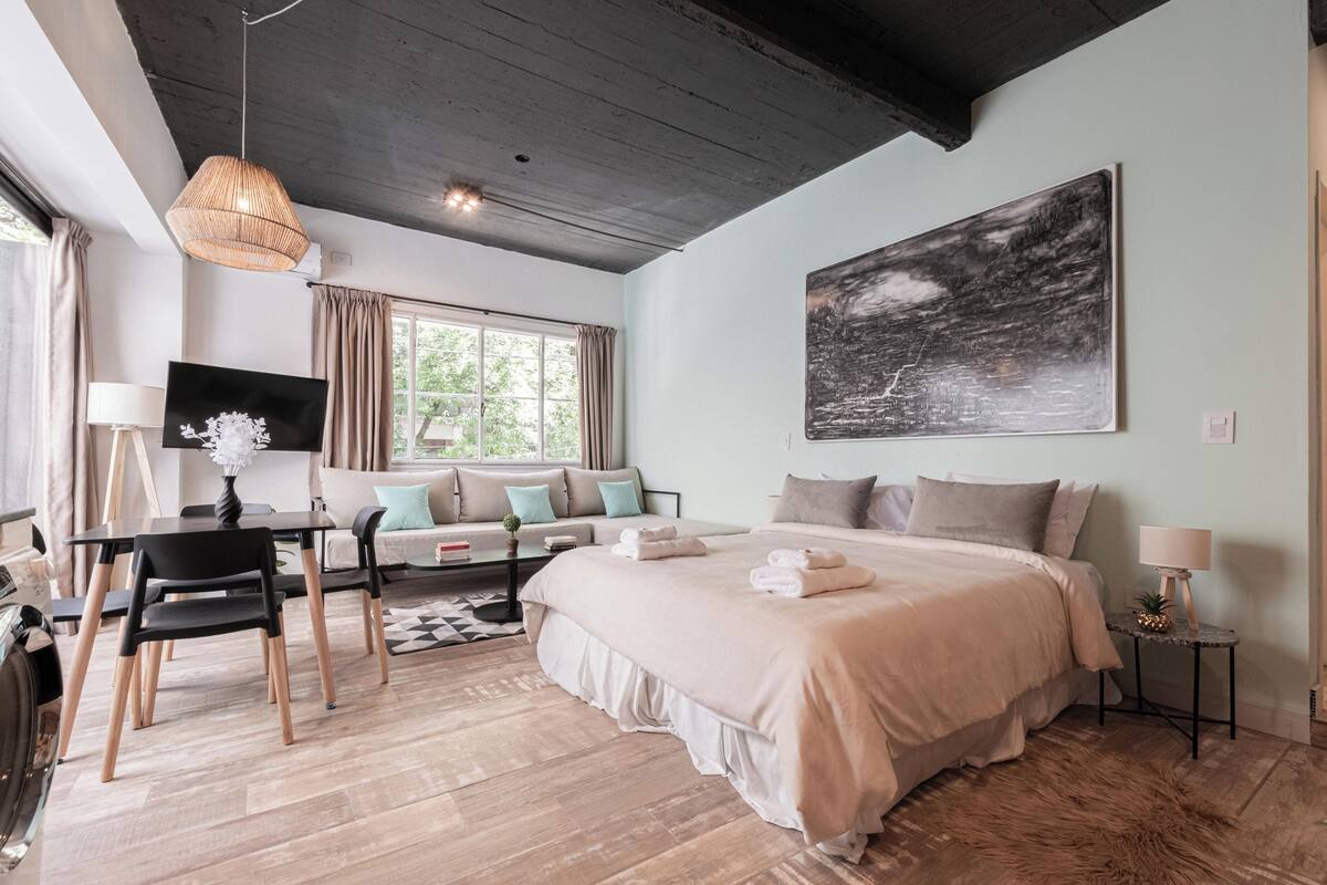 A modern bedroom with a large bed, a desk, and a sofa.
