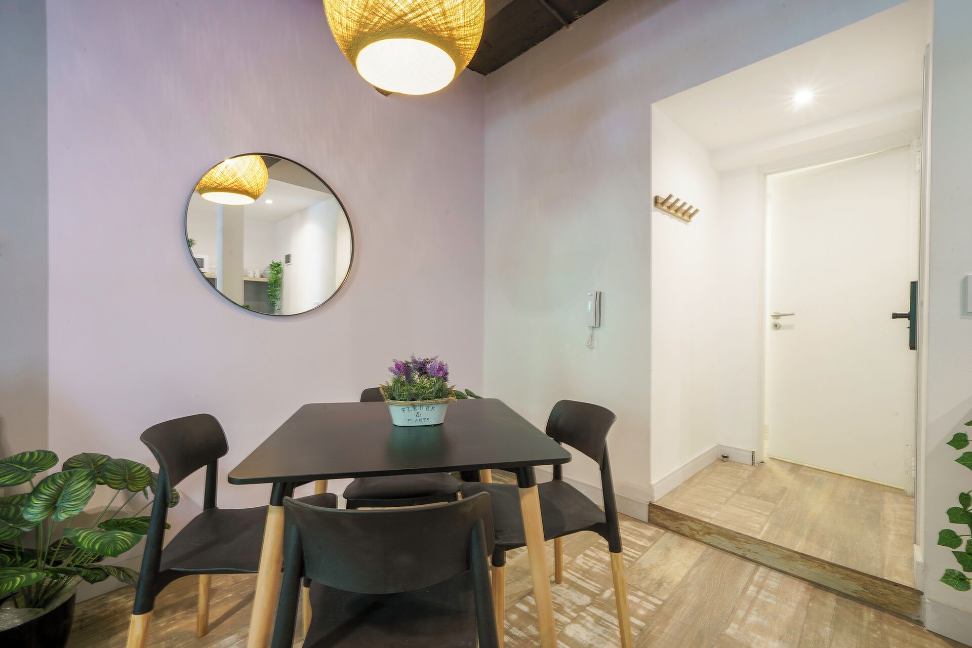 Uma área de refeições com mesa, cadeiras, um espelho e um vaso de planta.