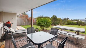 A covered patio with a barbecue grill, outdoor seating, and a view of a backyard. - Surfside Serenity (Anglesea)