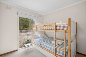 Une chambre avec des lits superposés donnant sur un jardin, avec une porte coulissante.
