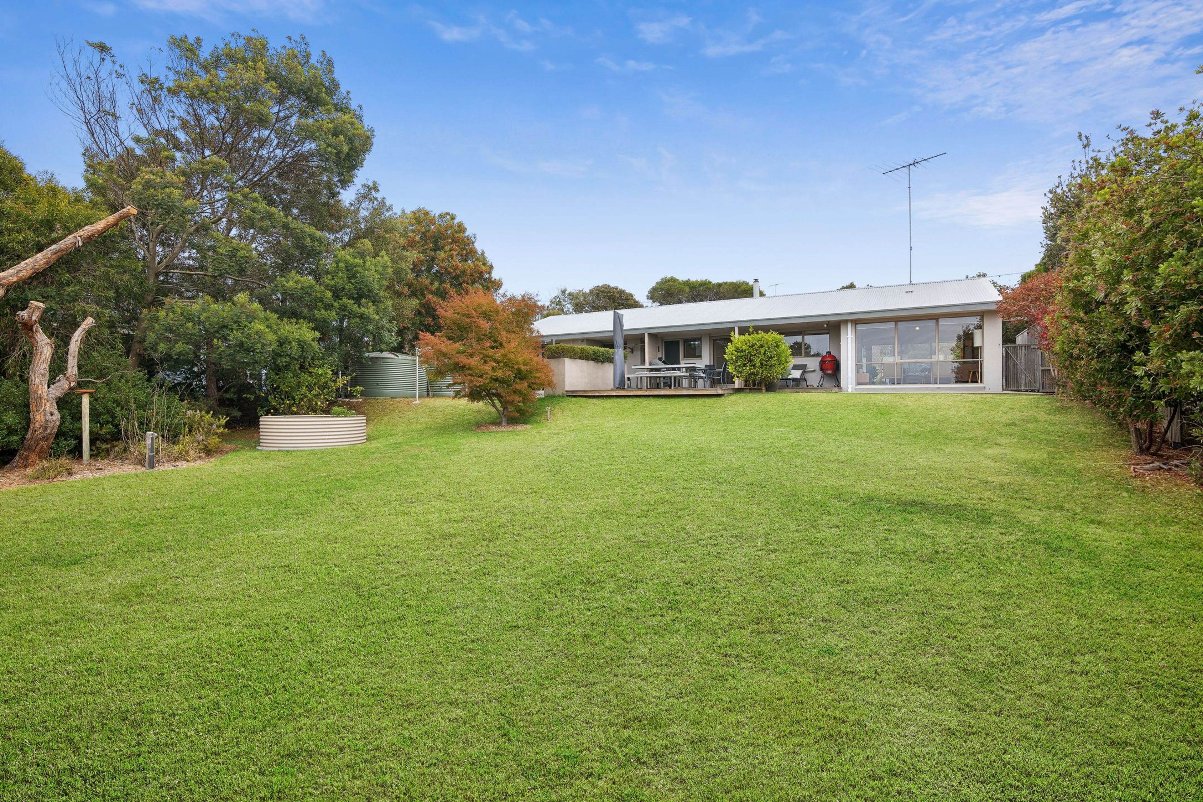 A modern house with a covered patio, a barbecue area, and a well-maintained lawn.