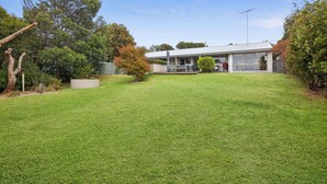 A modern house with a covered patio, a barbecue area, and a well-maintained lawn. - Surfside Serenity (Anglesea)