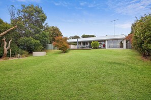 A modern house with a covered patio, a barbecue area, and a well-maintained lawn. - Surfside Serenity (Anglesea)