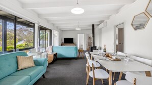 Un intérieur moderne comprenant un canapé, une table à manger, des chaises, un téléviseur et une cheminée.