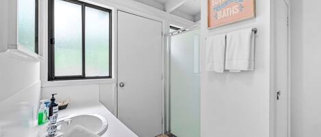 A modern bathroom with a large window, a shower, and a sign that reads 'even butterflies need to take baths.'