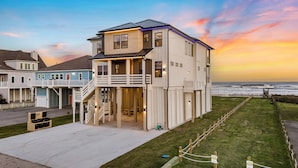 Uma casa à beira-mar com varanda, escadaria e vista para o oceano.