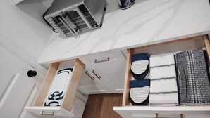 A kitchen with a microwave, a coffee maker, and a drawer with folded clothes.