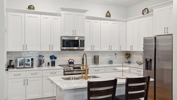 A modern kitchen with white cabinets, stainless steel appliances, and a central island with two chairs.