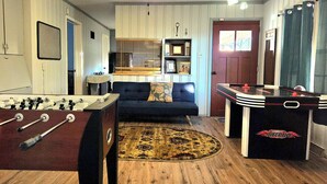 A room with a foosball table, a sofa, and a pool table.