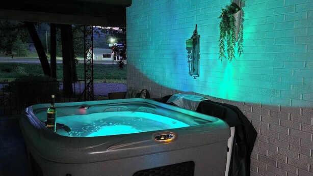 A hot tub with a brick wall and a hanging planter in the background.