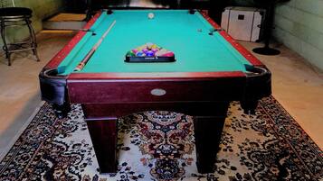Une table de billard avec un tapis à motifs, une queue de billard et une bille.