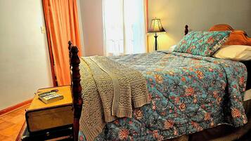 A bedroom with a bed, a nightstand, a lamp, and a suitcase.