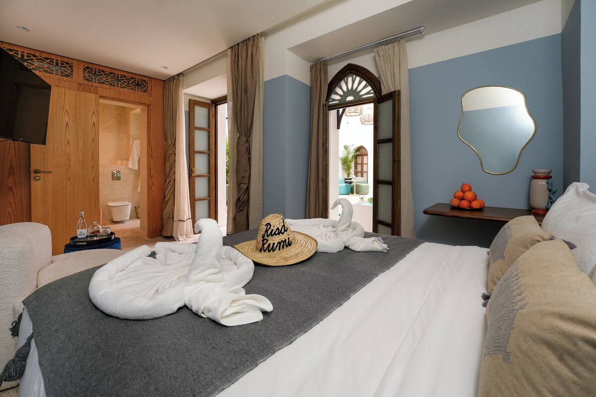 A hotel room with a bed, a wooden wardrobe, a bathroom, and a view of the outside.