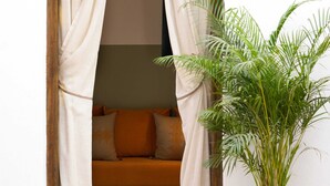Una habitación acogedora con una cama, una planta en maceta y un reposapiés morado.